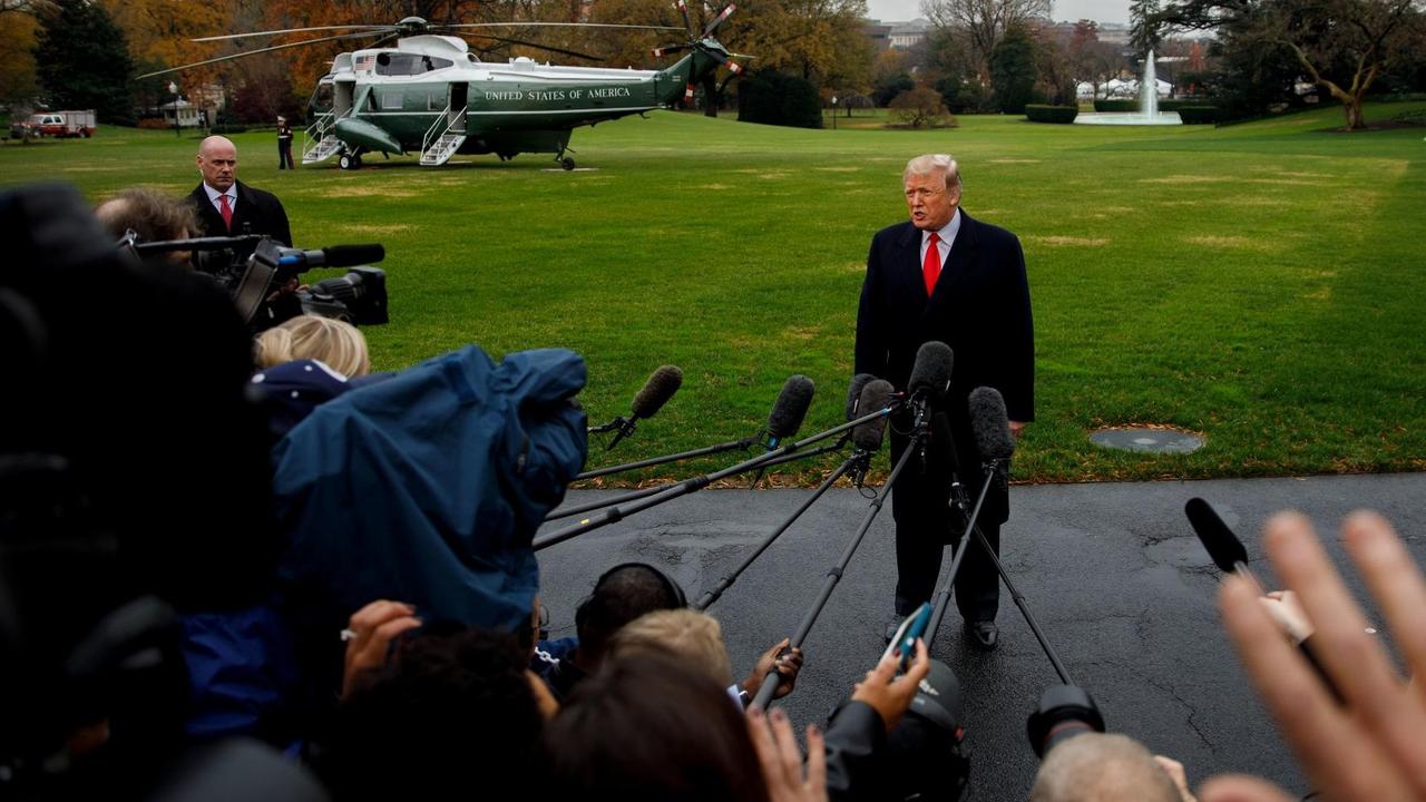 US-Präsident Donald Trump spricht in Mikrofone, die ihm an Angeln von Reportern entgegengehalten werden.