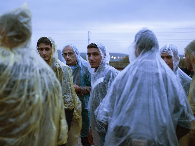 Flüchtlinge an der mazedonisch-griechischen Grenze mit Regencapes
