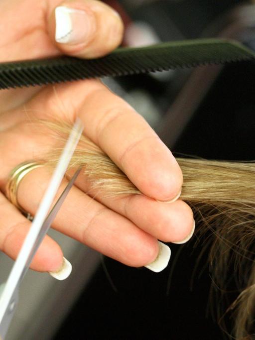 Eine Friseurin schneidet einem Kunden die Haare. 