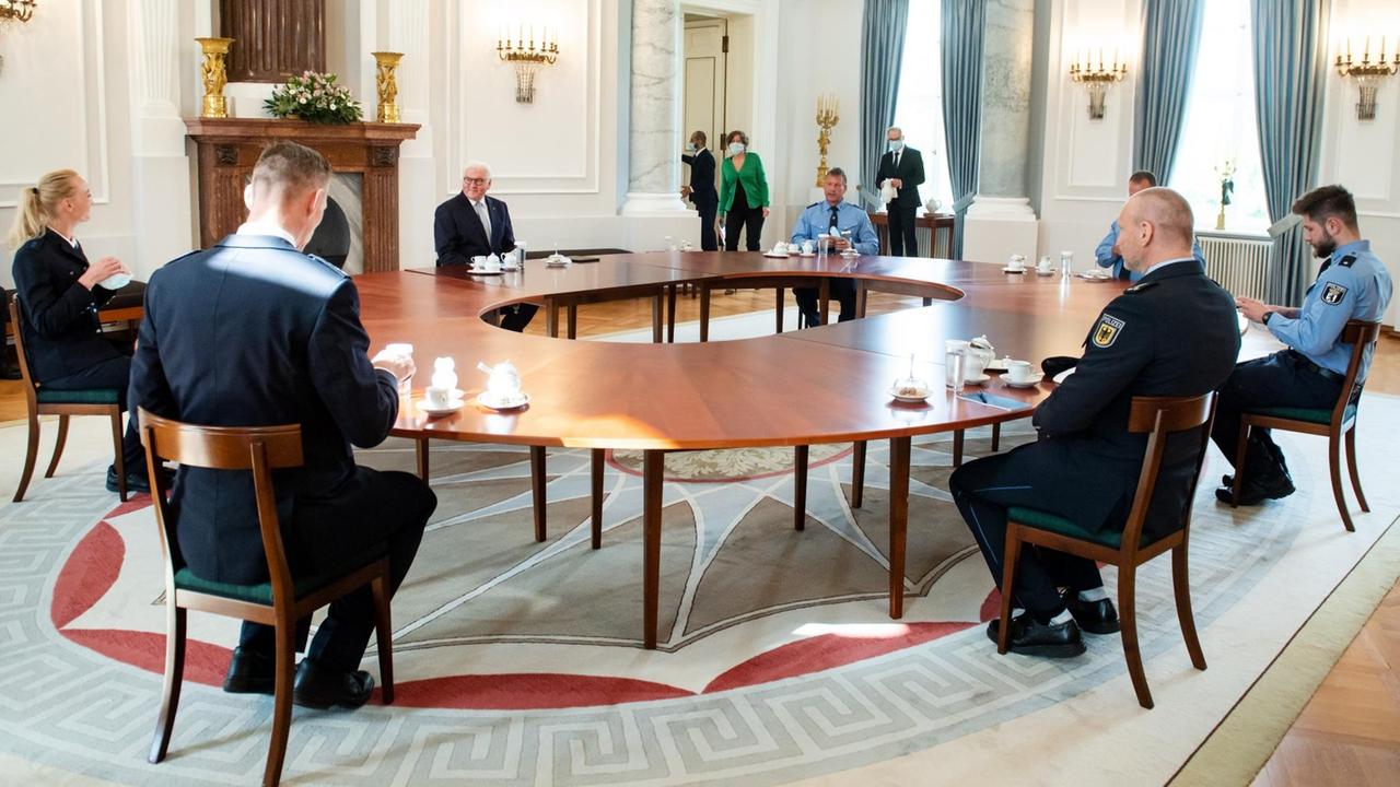Bundespräsident Frank-Walter Steinmeier und die Polizistinnen und Polizisten sitzen um einen großen, runden Tisch herum.