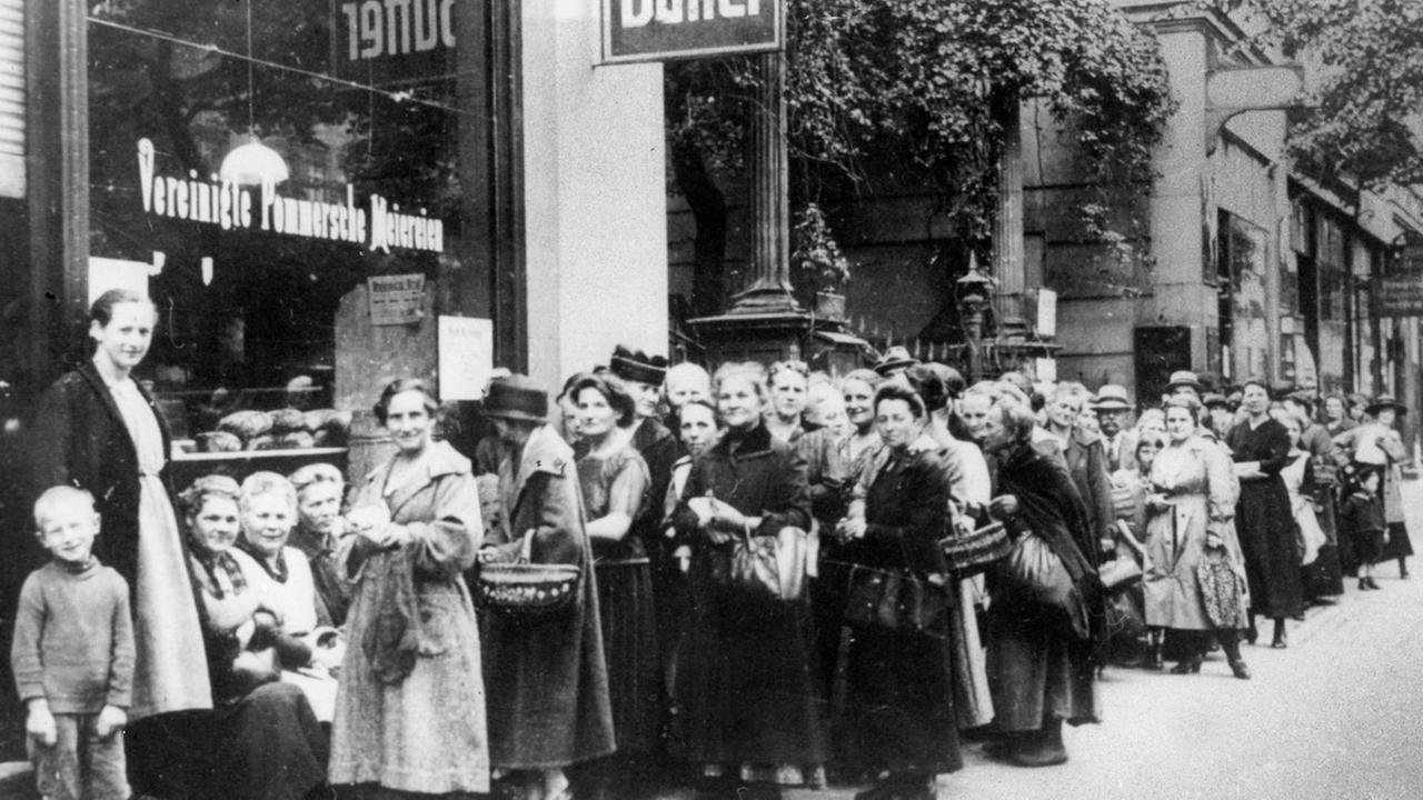 Schwarzweiß Fotografie mit einer Schlange von Menschen vor einem Lebensmittelladen im 1. Weltkrieg.