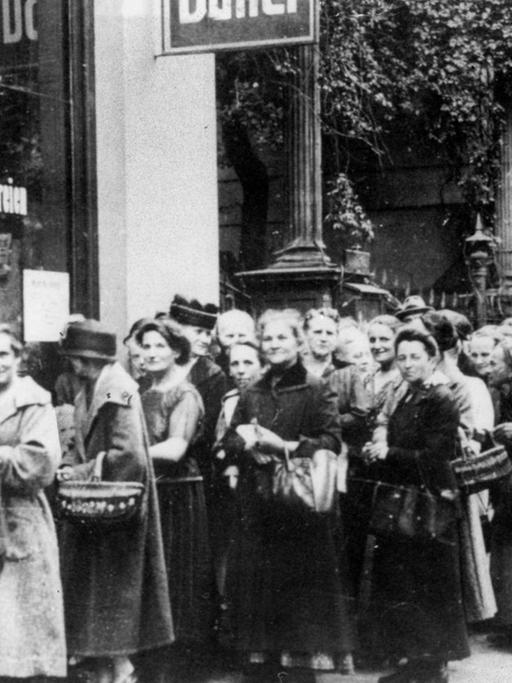 Schwarzweiß Fotografie mit einer Schlange von Menschen vor einem Lebensmittelladen im 1. Weltkrieg.