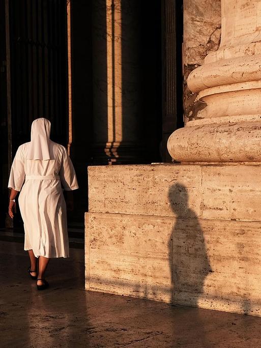 Eine Nonne betritt die St. Peter's Basilica im Vatikan in Rom in der Dämmerung.