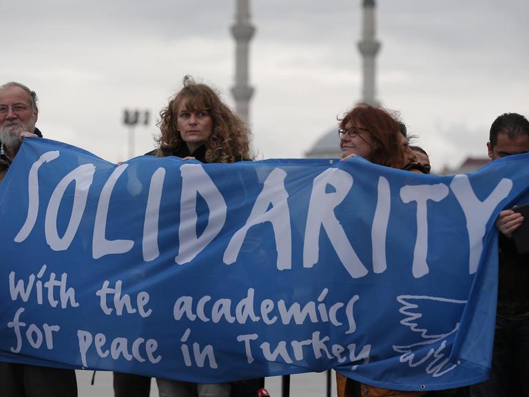 Eine Delegation von Akademikern und Menschenrechtsaktivisten aus Deutschland demonstriert vor einem Gericht in Istanbul und hält dazu ein Banner hoch, auf dem sie Solidarität mit den Angeklagten fordern..