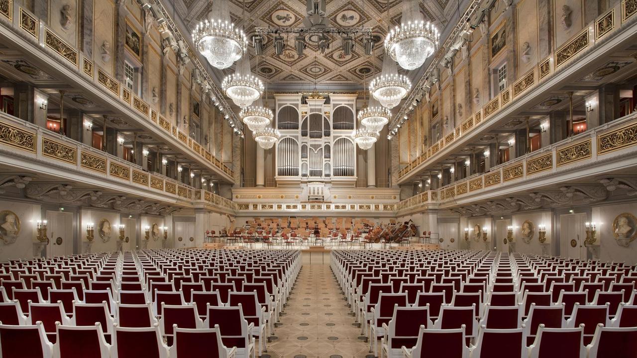 Ein mittiger Blick in den klassizistischen Saal mit roten Stühlen, Kronleuchtern, Rängen hin zur Bühne, die von einer großen Orgel gekrönt wird.
