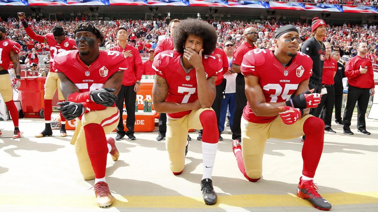Der Quaterback Colin Kaepernick (Mitte) von den San Francisco 49ers und zwei Mitspieler knien während der Nationalhymne bei einem Match der National Football League. 