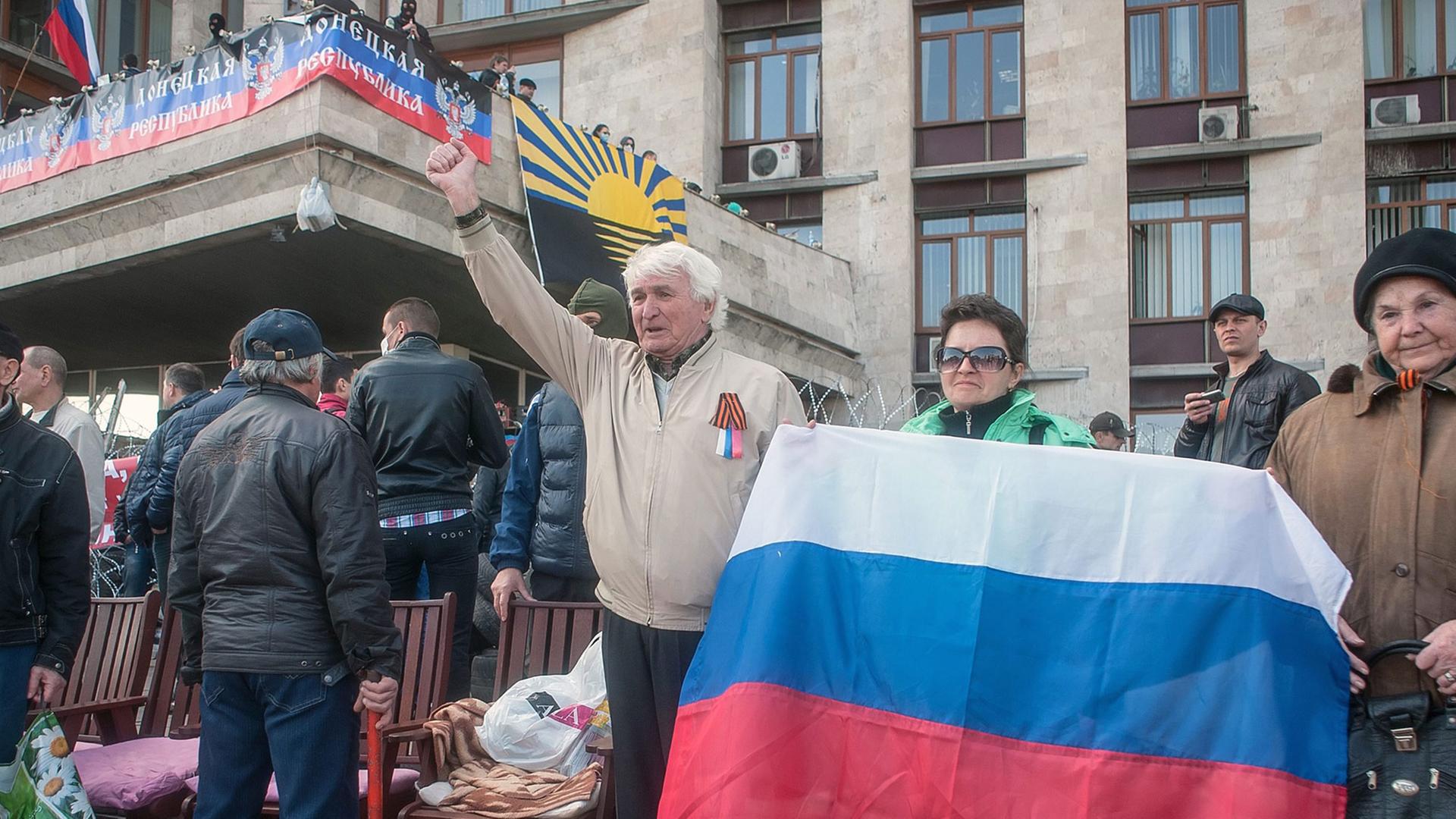 Prorussische Demonstranten in Donezk halten eine russische Fahne vor sich. Prorussische Demonstranten in Donezk halten eine russische Fahne vor sich.