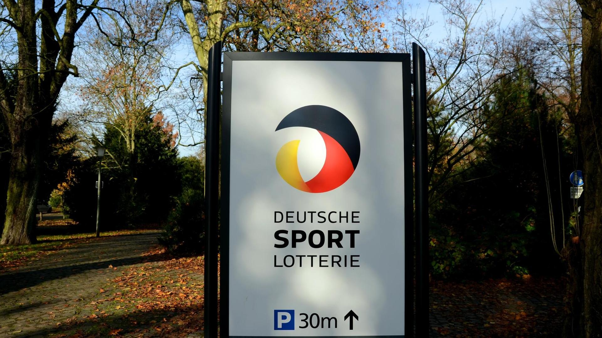 Ein Hinweisschild mit dem Logo "Deutsche Sport - Lotterie" steht an einem Weg im Schönhausenpark in Krefeld (Nordrhein-Westfalen).