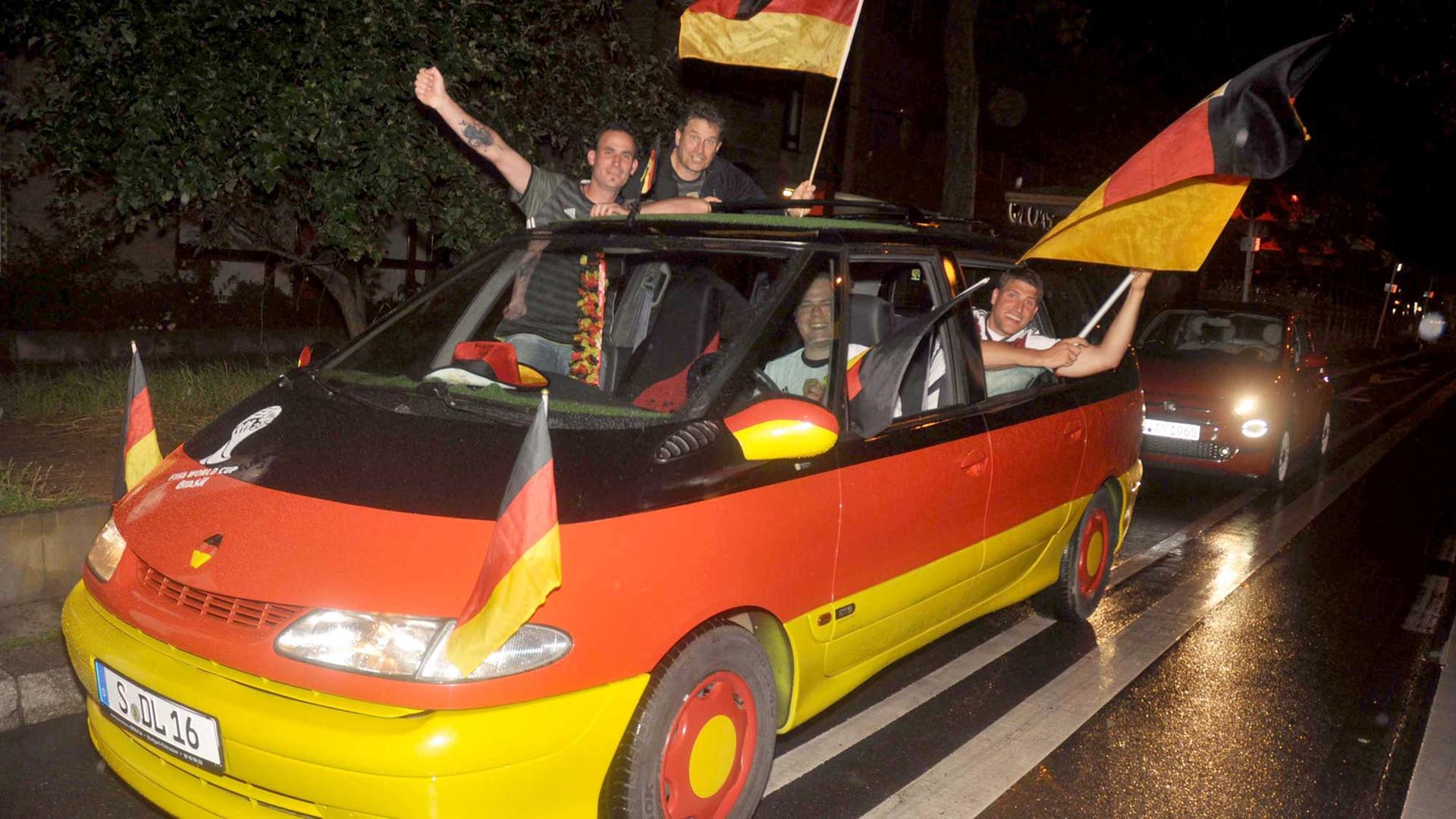 Deutsche Fans feiern den Sieg gegen die Ukraine und einem schwarz-rot-gold-geschmückten Auto