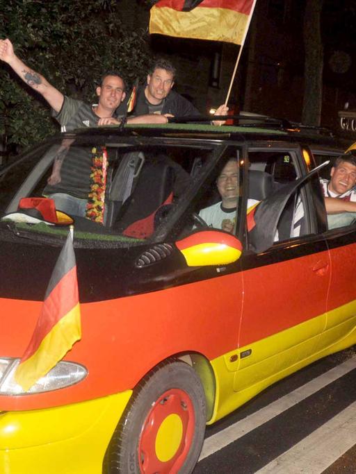 Deutsche Fans feiern den Sieg gegen die Ukraine und einem schwarz-rot-gold-geschmückten Auto