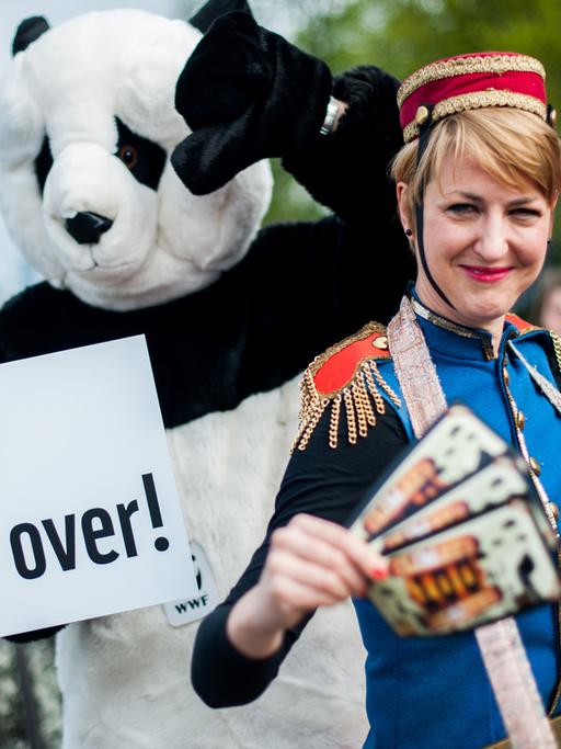 WWF-Aktivisten halten am 11.04.2014 in Berlin ein Schild mit der Aufschrift "Game over!" und Flugblätter in Form von Spielscheinen für Spielautomaten.
