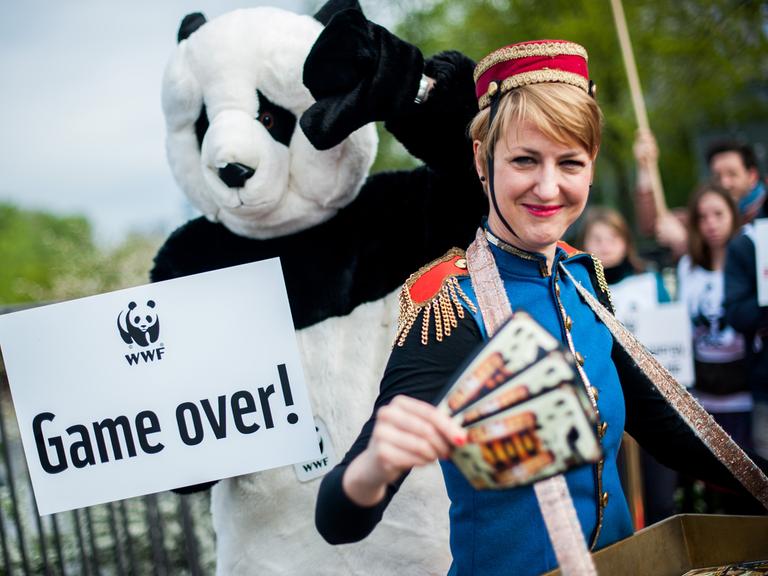 WWF-Aktivisten halten am 11.04.2014 in Berlin ein Schild mit der Aufschrift "Game over!" und Flugblätter in Form von Spielscheinen für Spielautomaten.