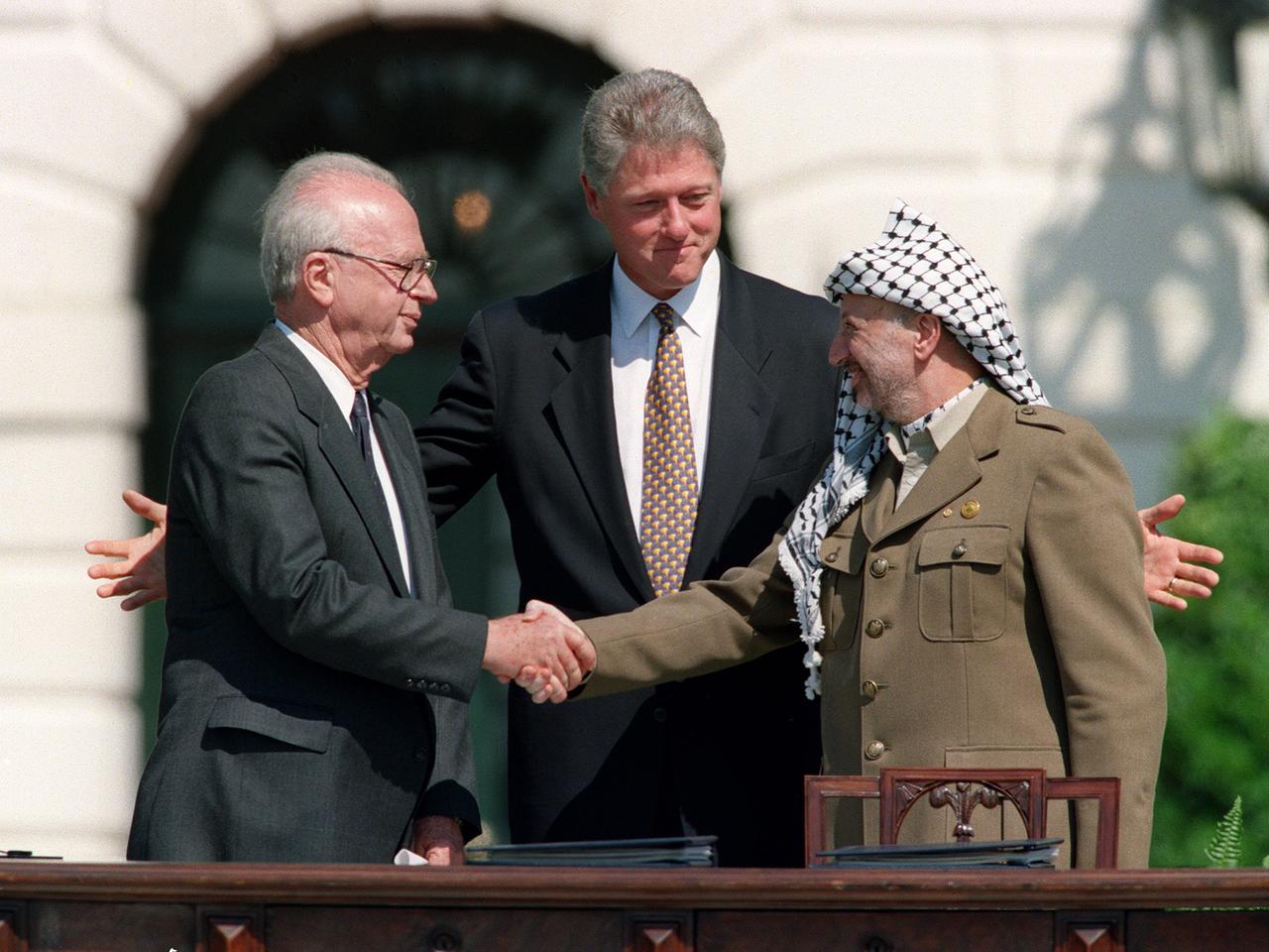 Jitzhak Rabin und Jassir Arafat schütteln sich im Beisein von Bill Clinton die Hände.
