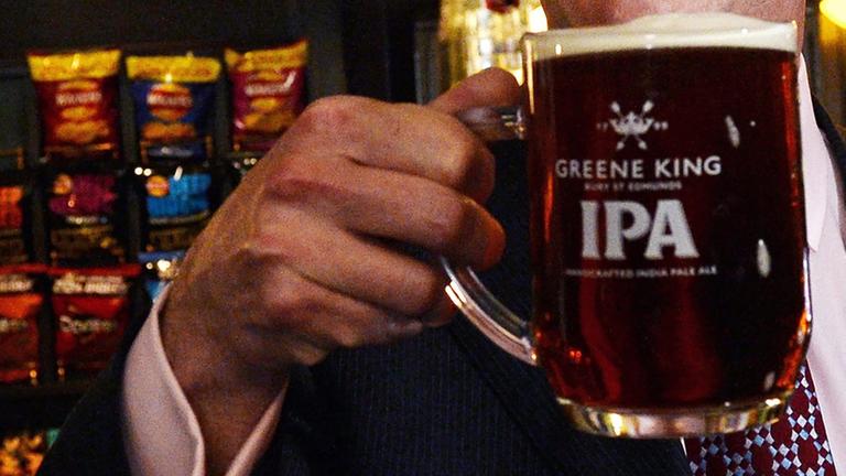 Eine Hand hält ein Bier in einem englischen Pub