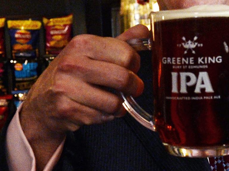 Eine Hand hält ein Bier in einem englischen Pub