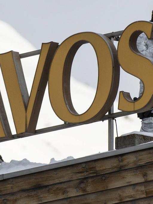 Vermummte Beamte der Schweizer Polizei in Wintermontur und Waffen stehen auf dem Dach des Kongresshotels in Davos.