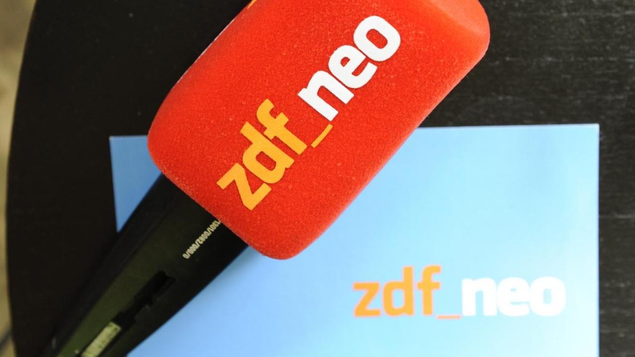 Ein Mikrofon und eine Moderatorenkarte mit dem Logo von ZDFneo liegen auf einem Tisch.
