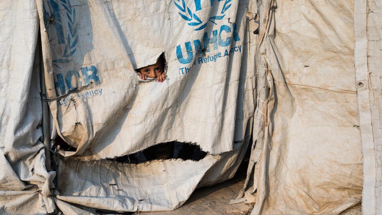 Ein kleiner Junge schaut durch das Loch einer Zeltplane im Roj Camp. Dort leben auch ausländische Frauen, die früher Teil des "islamischen Staates" waren. Ihre Ehemänner wurden meist getötet oder verhaftet.