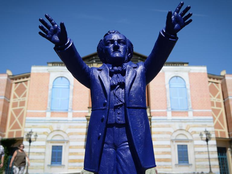 Ein Plastik-Wagner des Künstlers Ottmar Hörl "dirigiert" vor dem Königsportal des Festspielhauses auf dem Grünen Hügel in Bayreuth (Bayern).