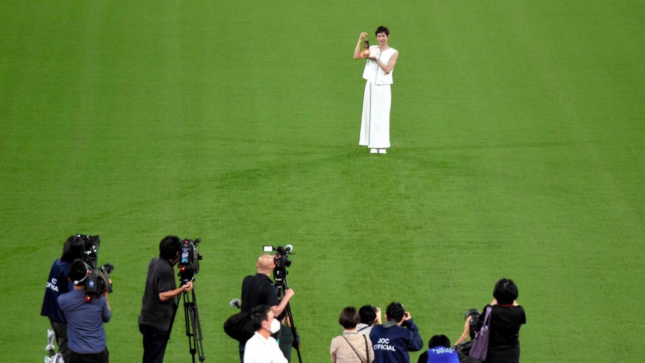 Die japanische Schwimmerin Rikako Ikee hält während einer Zeremonie im Nationalstadion eine Laterne mit der olympischen Flamme in den Händen.
