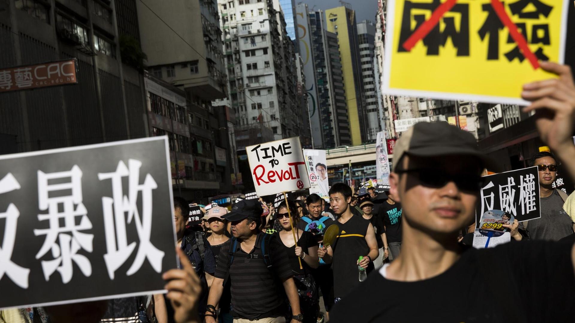 Demonstranten halten Schilder mit chinesischen Schriftzeichen hoch.