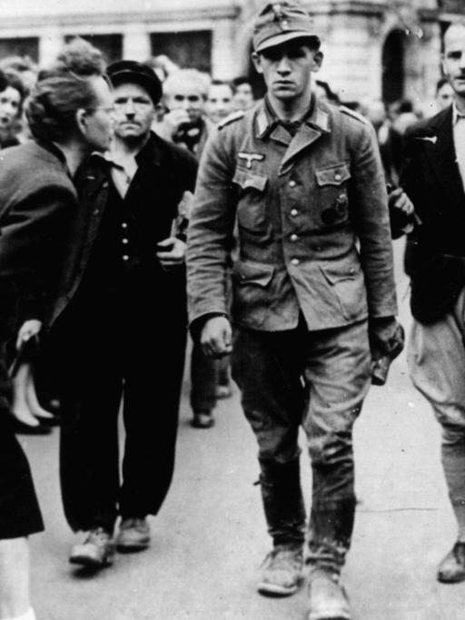 Französische Soldaten führen einen deutschen Kriegsgefangenen, der von der Bevölkerung beschimpft wird, ab - Sommer 1944.