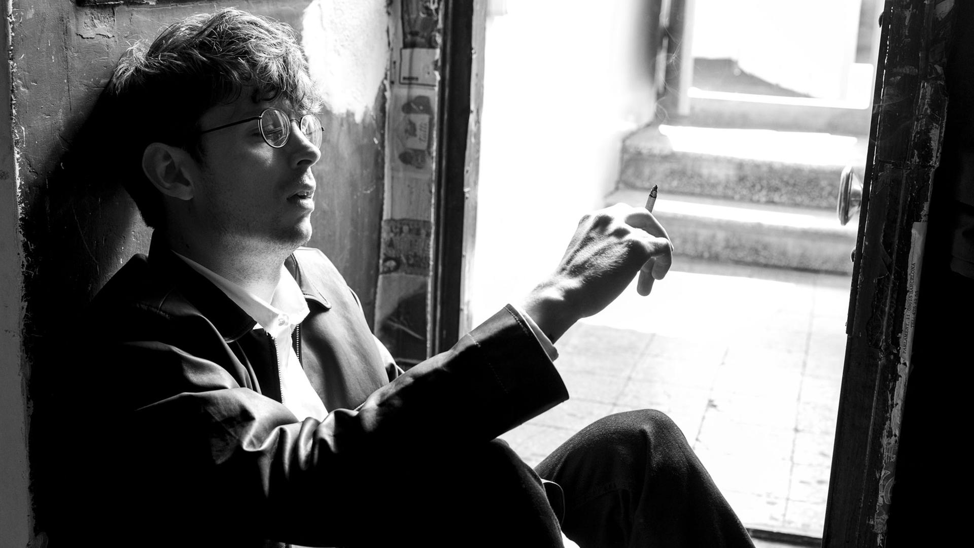 Musiker Albin Lee Meldau sitzt rauchend vor einer offen Tür.