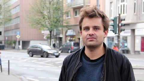 Der Regisseur und Dramaturg Julian Pörksen steht an einer Straße in Köln