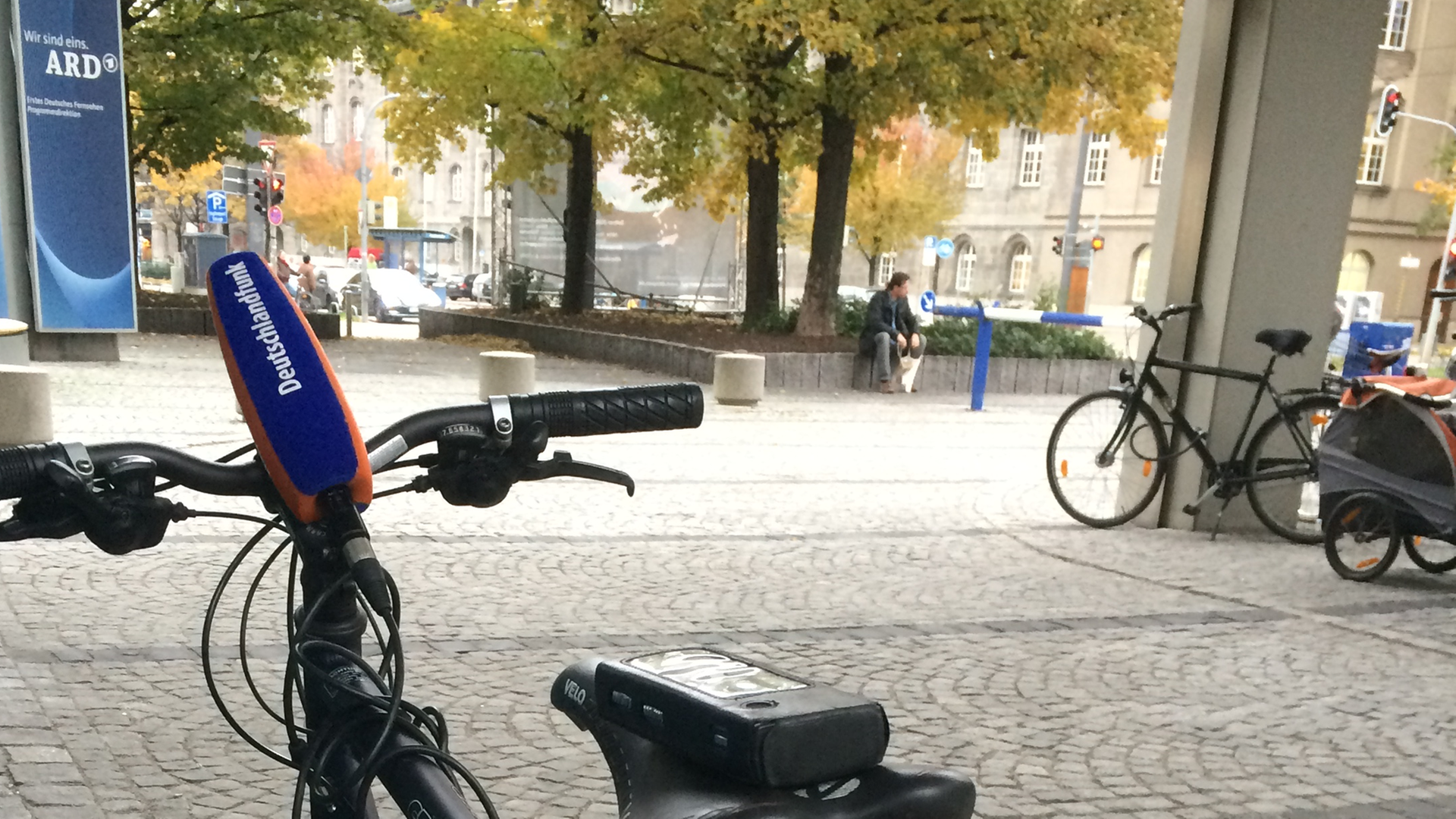 Ein Fahrrad, auf dessem Sattel ein Aufnahmegerät liegt. Im Hintergrund das ARD-Studio München. Ein Fahrrad, auf dessem Sattel ein Aufnahmegerät liegt. Im Hintergrund das ARD-Studio München.