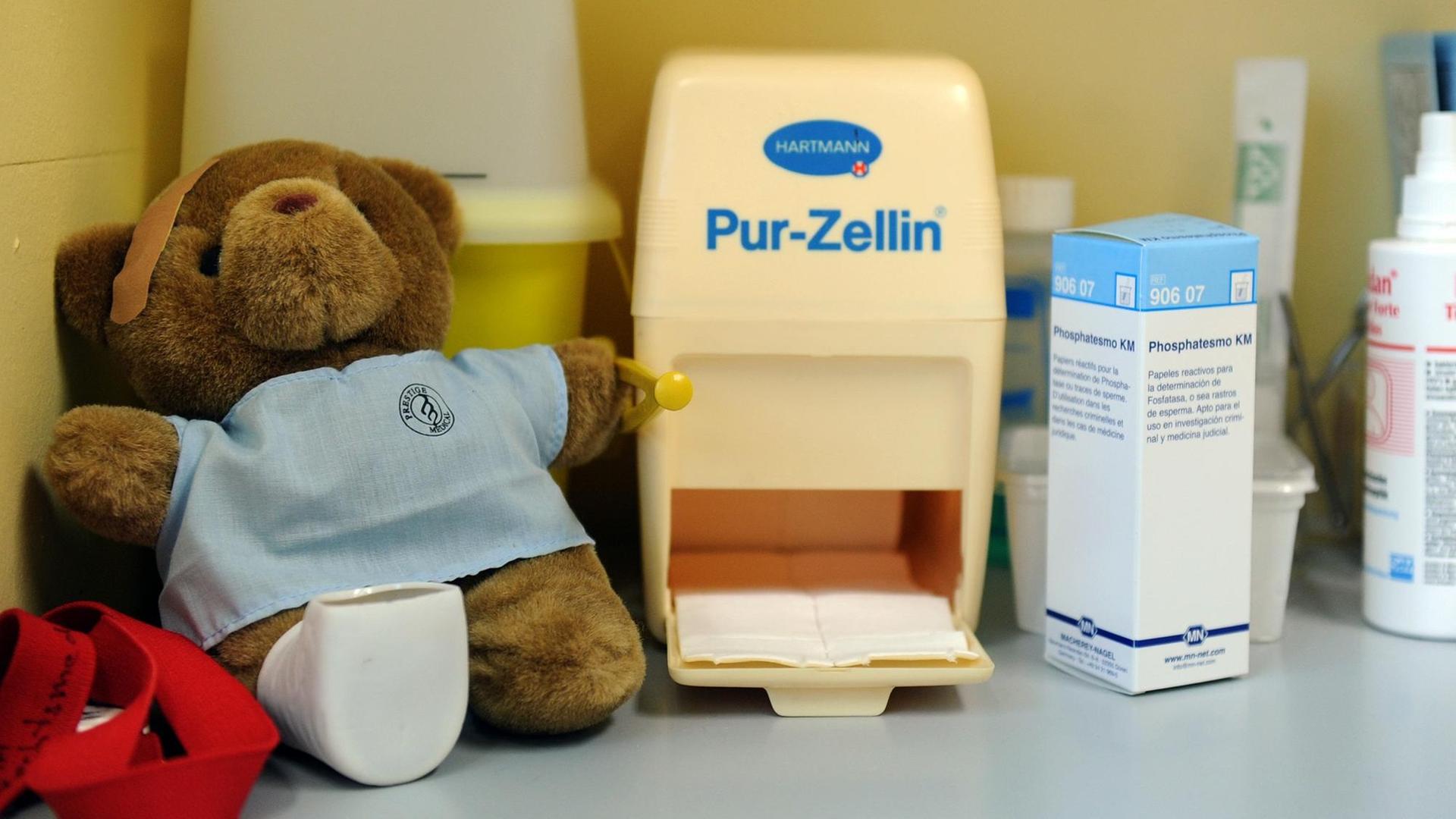 Ein Teddybär sitzt in einer Kinderschutzambulanz im Untersuchungszimmer zwischen Arzneimitteln.
