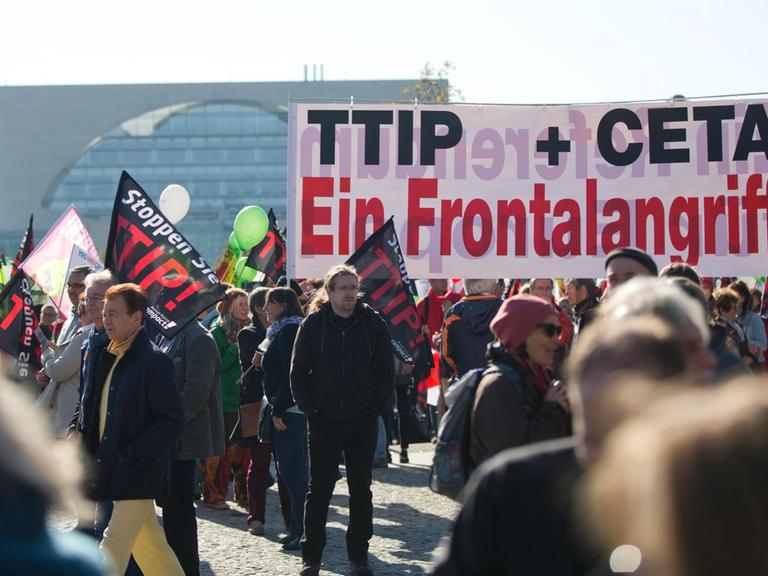 Ein Transparent mit der Aufschrift "TTIP + CETA Ein Frontalangriff" ist bei einer Demonstration gegen das transatlantische Handelsabkommen TTIP (USA) und Ceta (Kanada) am 10.10.2015 in Berlin zu sehen.