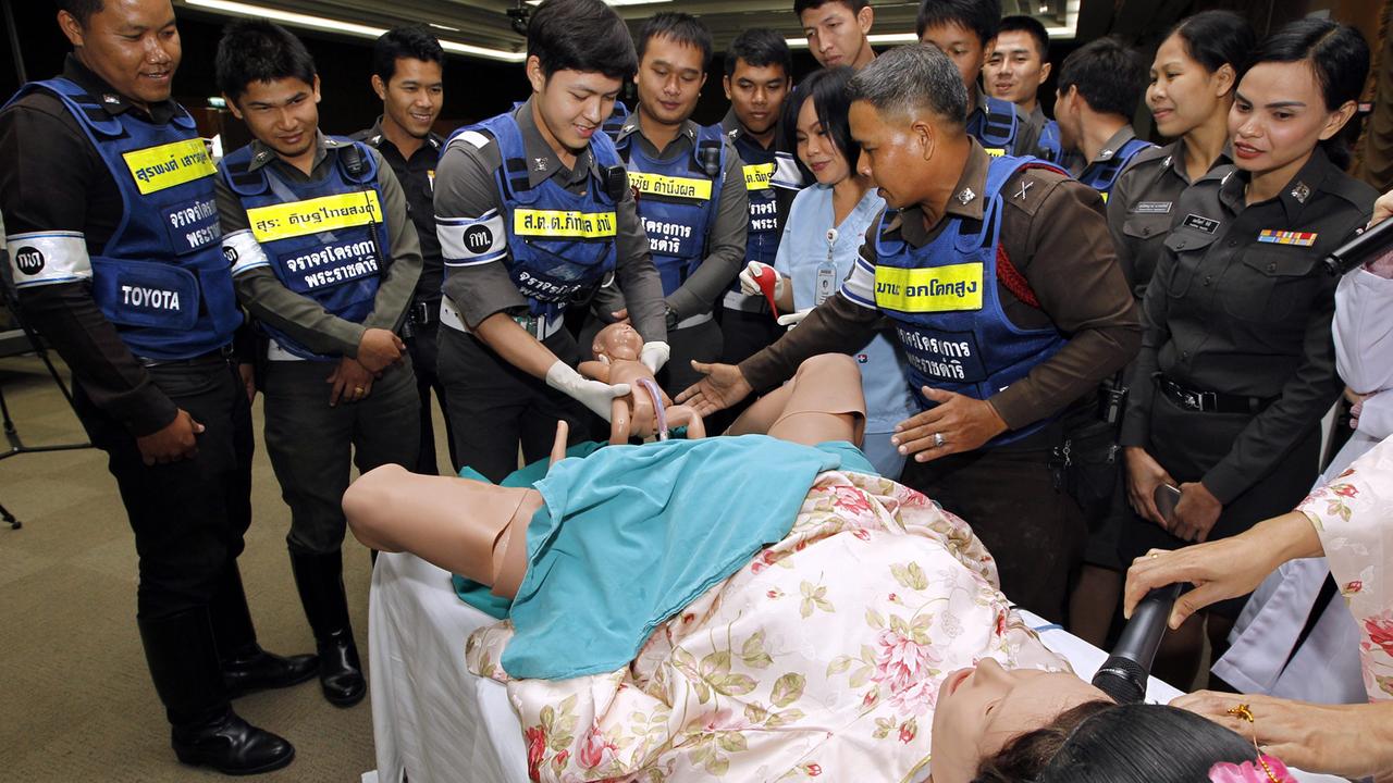 Thailändische Verkehrspolizisten bei einer Geburtsübung in Bangkok. Wegen notorischer Dauerstaus mussten schon zahlreiche Frauen im Auto gebären.