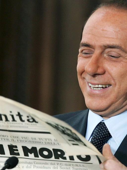Der italienische Ministerpräsident Silvio Berlusconi lächelt, als er in der Villa Madama in Rom eine«L'Unita»-Ausgabe aus dem Jahr 1953 mit Lobeshymnen auf den toten Sowjet-Diktator Stalin hochhält.