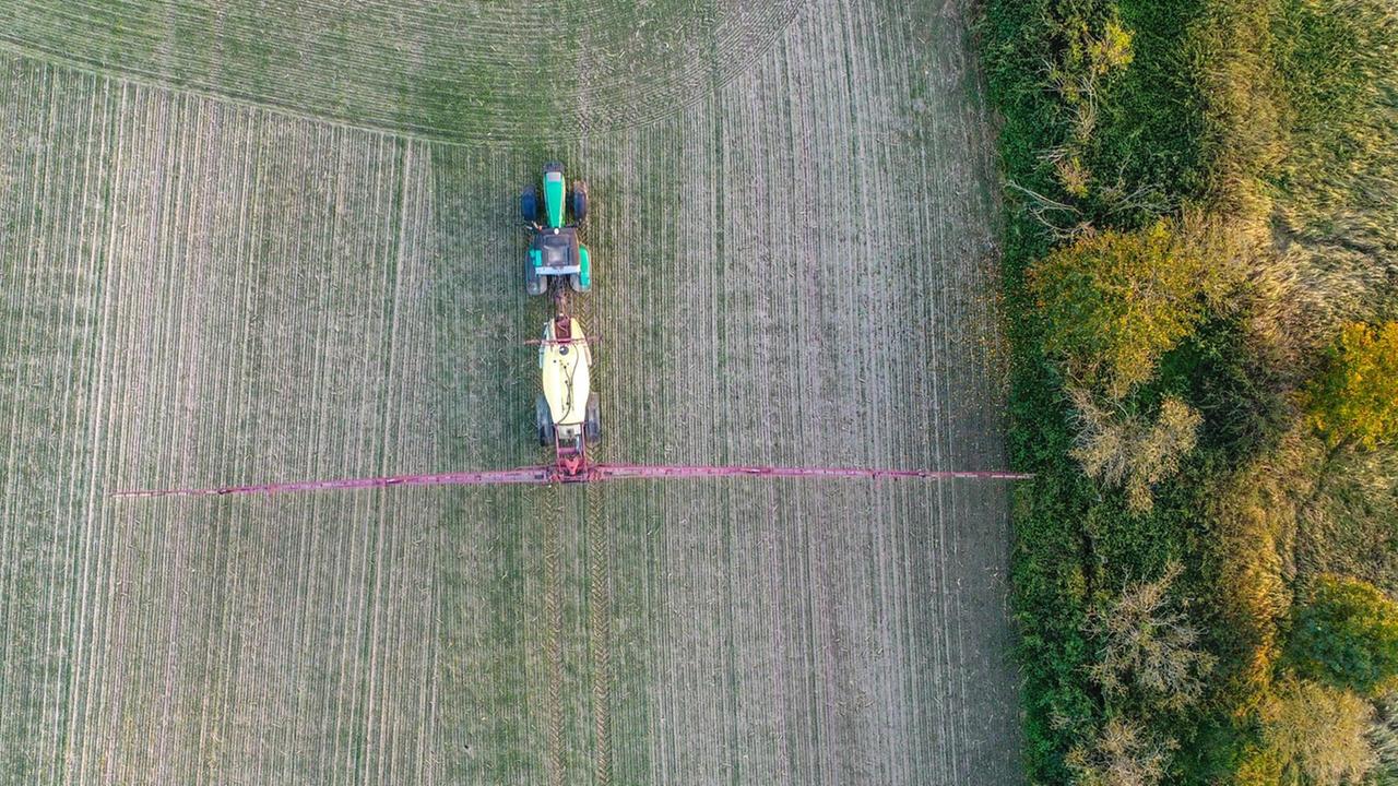 Ein Landwirt fährt mit einer Pflanzenschutzspritze über ein Feld 