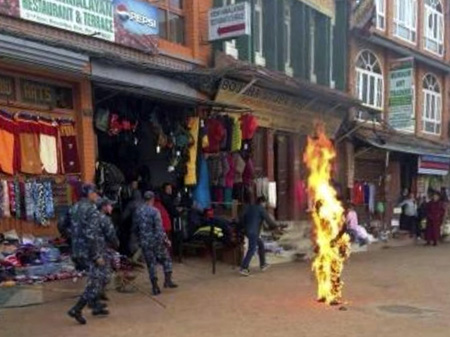 Ein brennender Mönch auf einer Straße, hinter ihm gehen mehrere Uniformierte vorbei