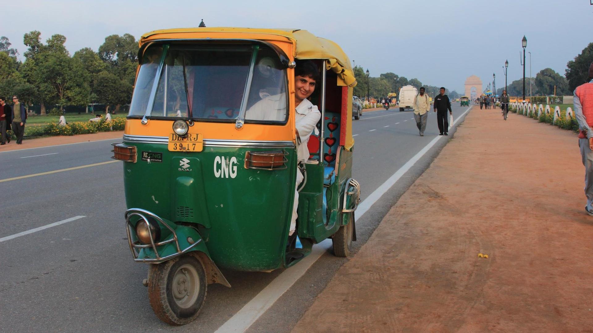 Eine gelb-grüne motorisierte Rikscha steht am Straßenrand. Eine gelb-grüne motorisierte Rikscha steht am Straßenrand.