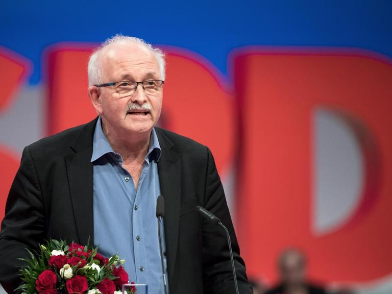 Udo Bullmann (SPD) an einem Rednerpult der SPD. Er hat Blumen in der Hand.