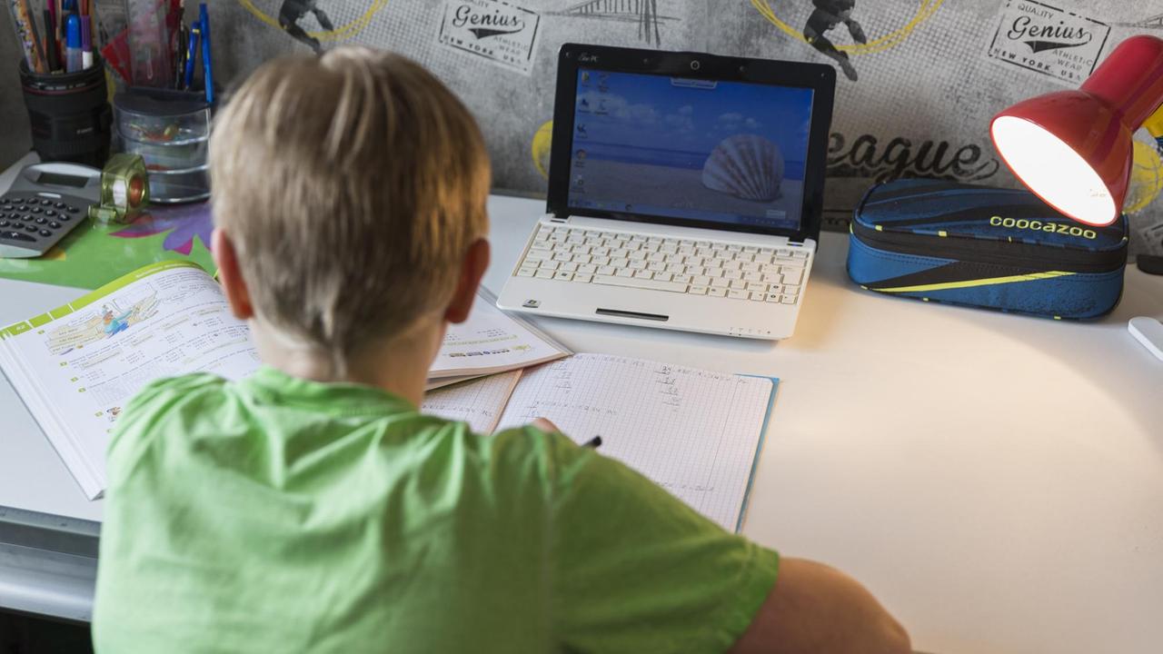 Ein junge sitzt an seinem Schreibtisch und erledigt seine Mathe-Aufgaben im Homeschooling