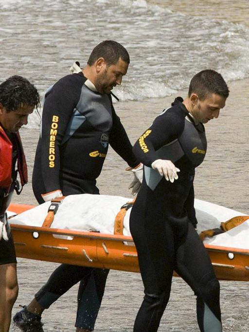 Feuerwehrleute tragen am Strand von Teneriffa den Leichnam eines ertrunkenen Flüchtlings aus Afrika