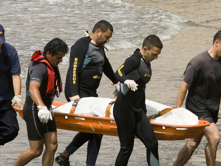Feuerwehrleute tragen am Strand von Teneriffa den Leichnam eines ertrunkenen Flüchtlings aus Afrika