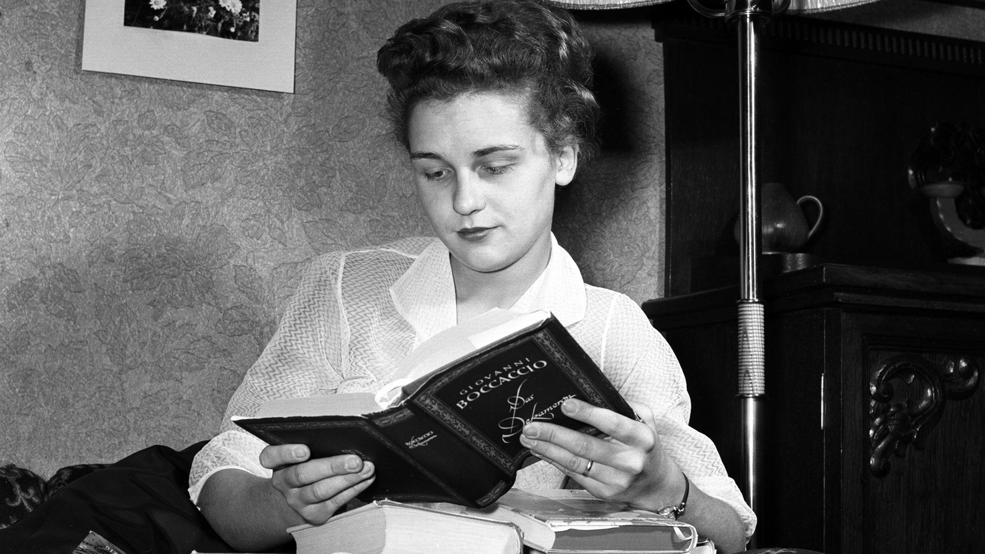 Eine junge Frau liest das Buch "Das Dekameron" von Giovanni Boccaccio auf dem Sofa ihres Hauses auf Rügen.