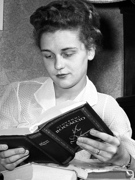 Eine junge Frau liest das Buch "Das Dekameron" von Giovanni Boccaccio auf dem Sofa ihres Hauses auf Rügen.