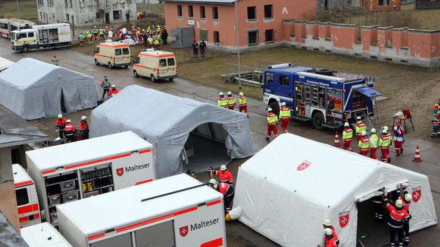 Mehrere Zelte und Fahrzeuge der Organisationen stehen auf einem Platz. 