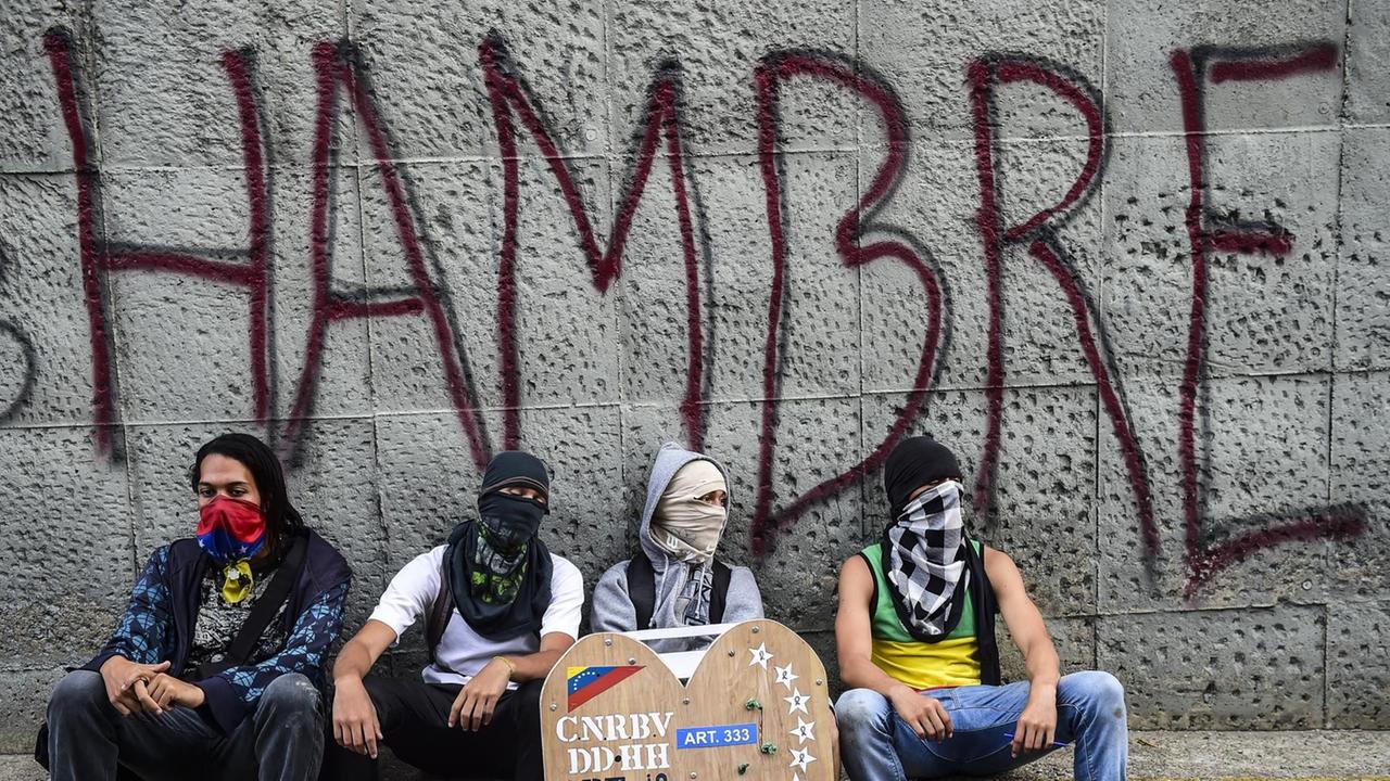 Oppositionelle Aktivisten sitzen vor einer einer Wand mit der Aufschrift "Hambre - Hunger"