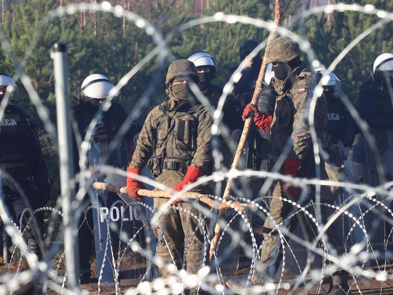 Polnische Sicherheitskräfte hinter Stacheldraht an der Grenze zu Belarus