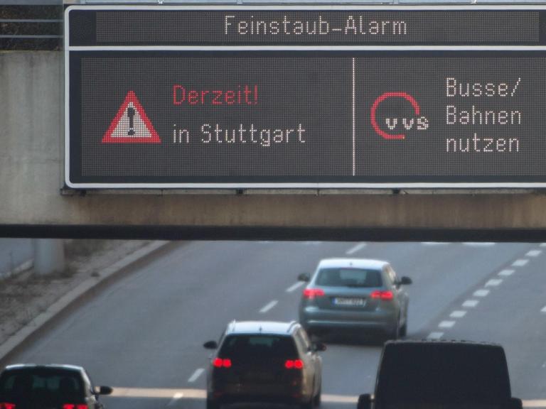 Autos fahren am 09.03.2016 in Stuttgart (Baden-Württemberg) durch die Innenstadt, während auf einer Anzeige ein Feinstaub-Alarm für die Umweltzone Stuttgart angezeigt und auf öffentliche Verkehrsmittel hingewiesen wird.