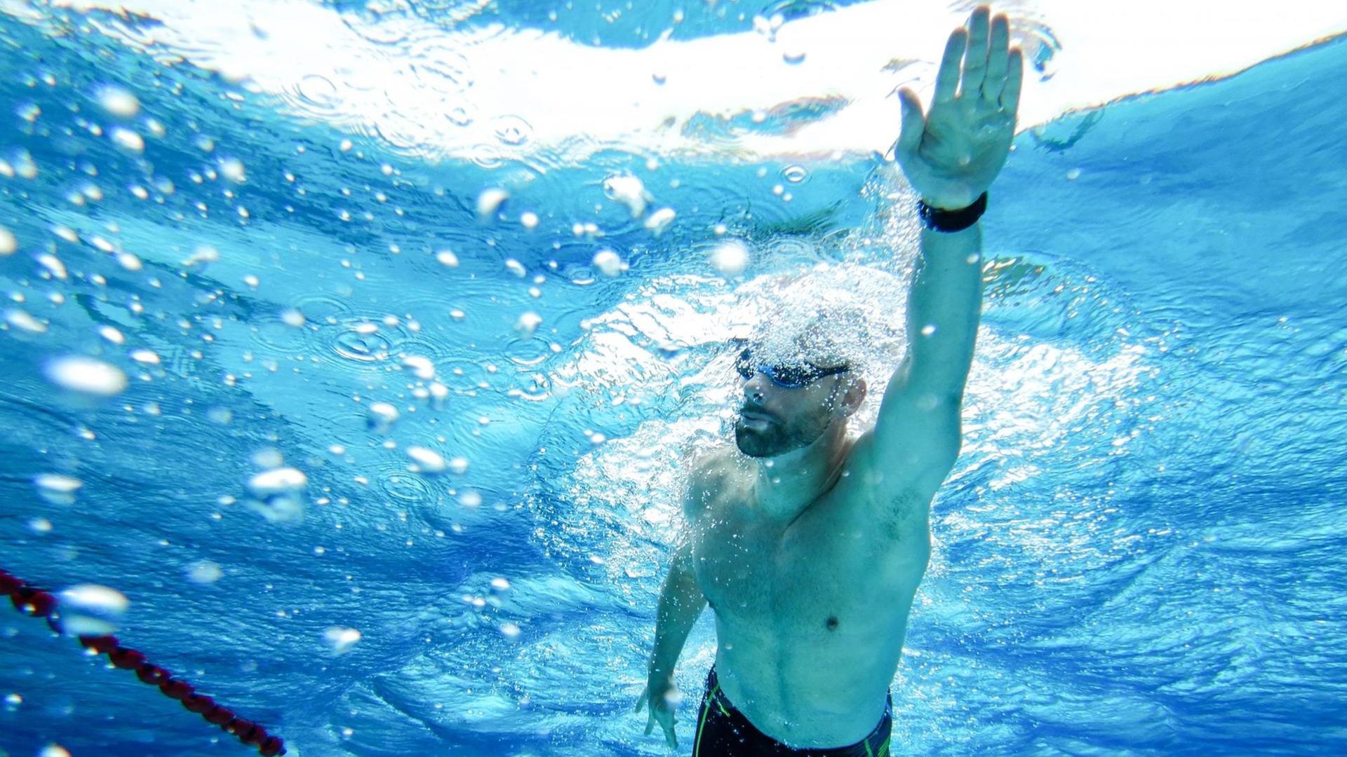 Aus der Unterwasser-Perspektive sieht man einen Profischwimmer beim Kraulen.