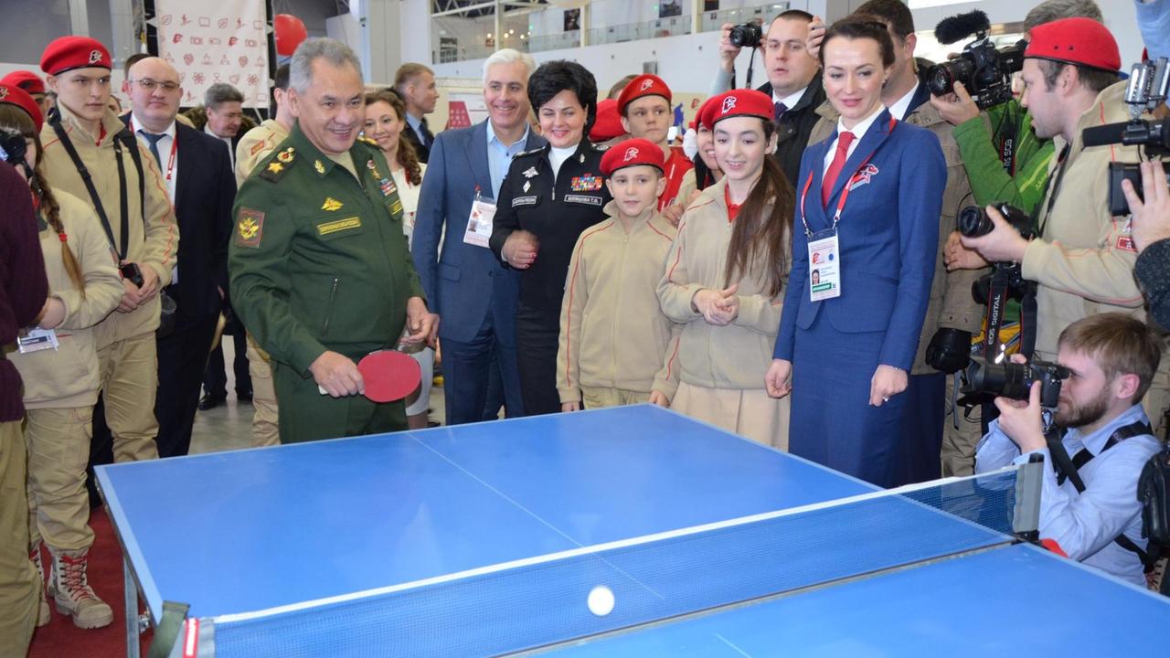 Verteidigungsminister Sergej Schoigu steht umringt von Jungarmisten an einer Tischtennisplatte und spielt einen Ball