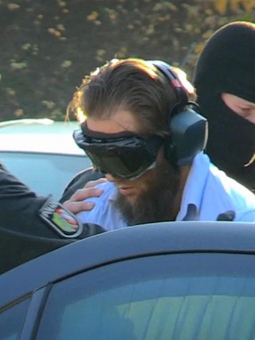 Salafistenprediger Sven Lau wird am 15.12.2015 in Mönchengladbach (Nordrhein-Westfalen) nach seiner Festnahme zu einem Auto geführt.