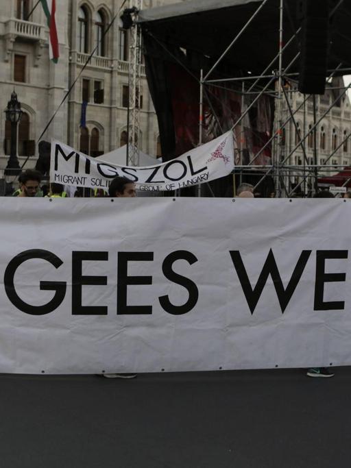 Eine Gruppe von Aktivisten protestiert gegen die Politik ihrer ungarischen Regierung und hält ein Schild, auf dem steht: Refugees welcome, Flüchtlinge willkommen.